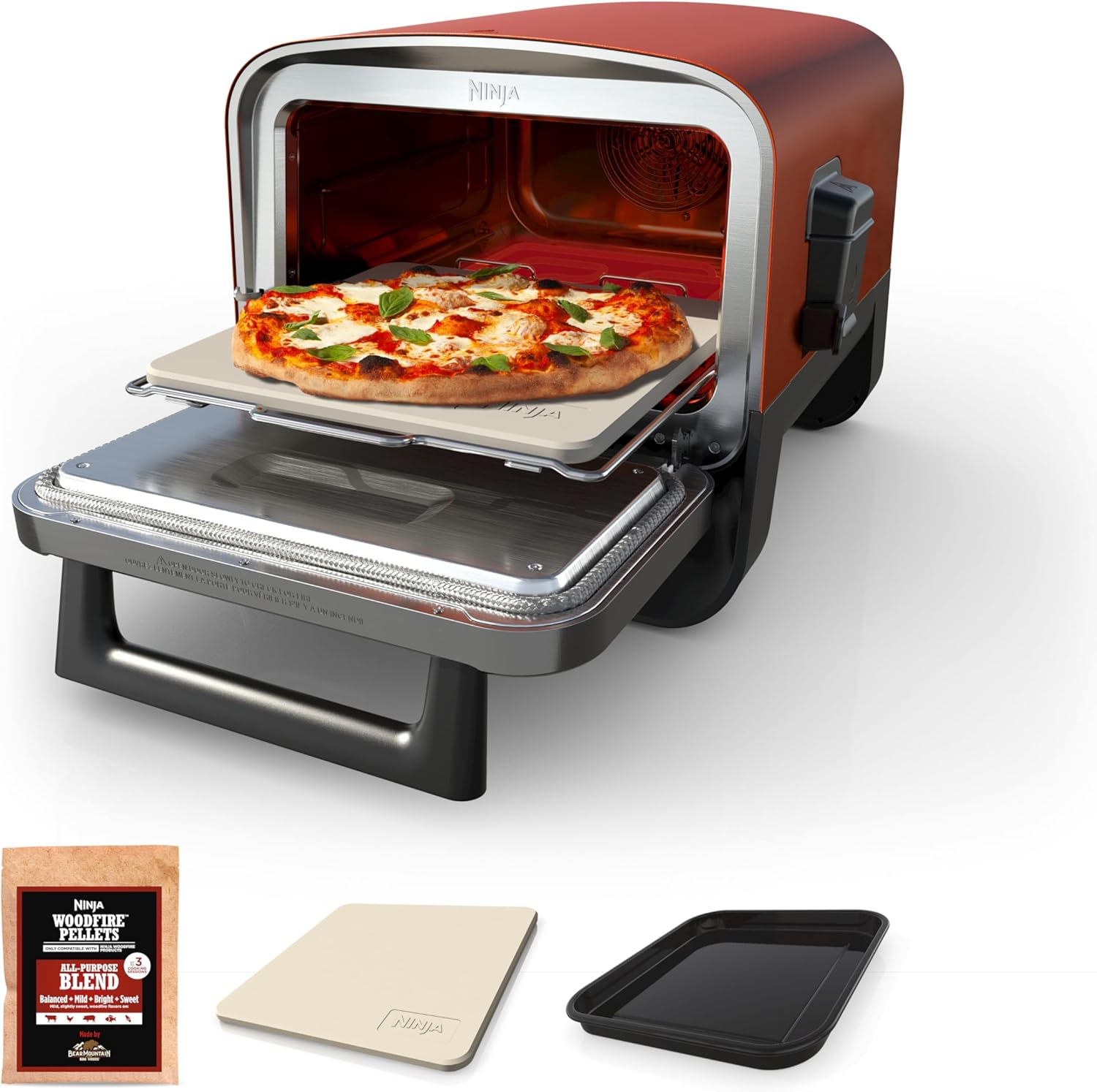 Ninja Woodfire Outdoor Oven OO101 in terracotta red with a freshly baked Neapolitan pizza visible inside, sitting on a wooden patio table