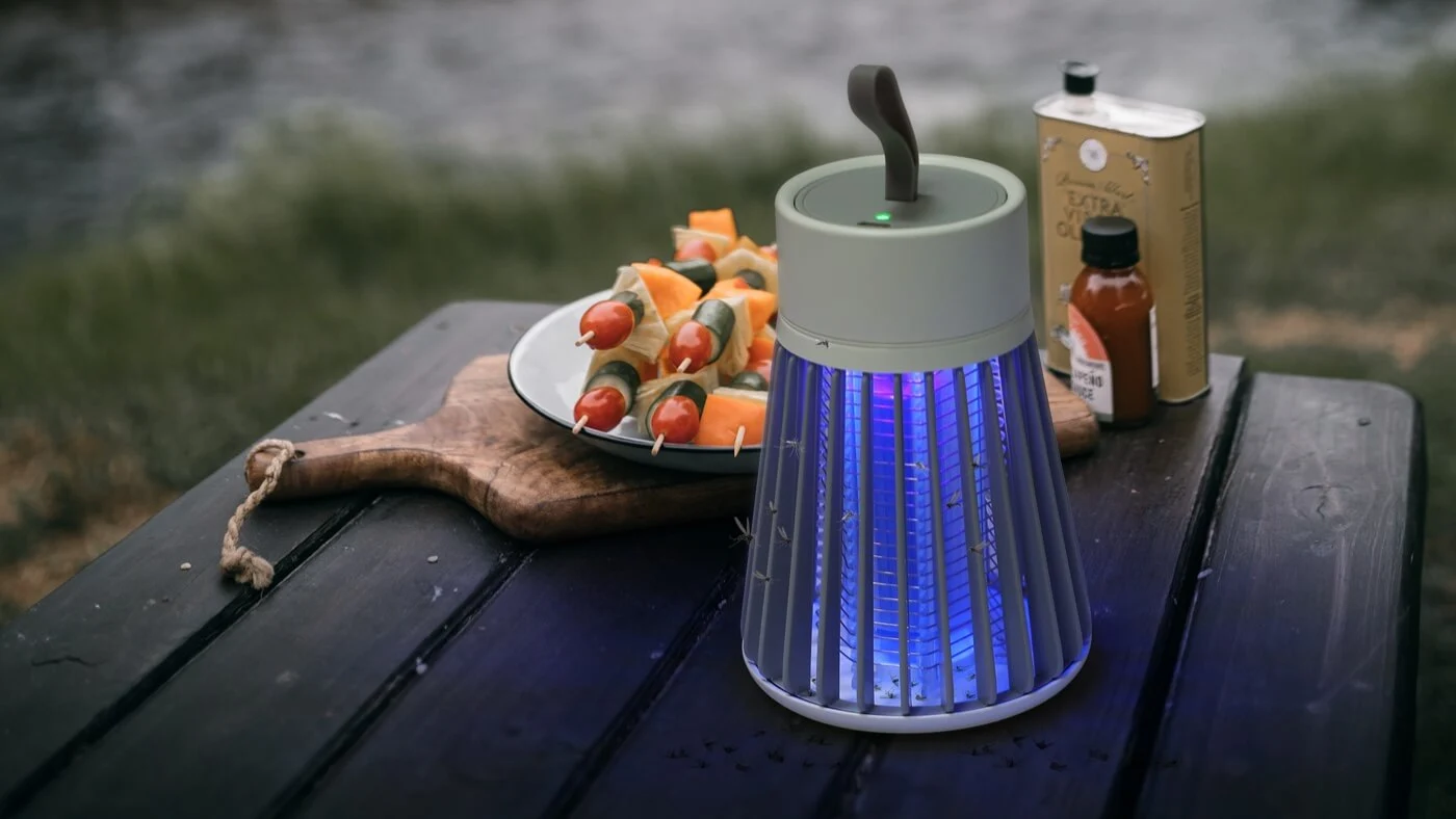 SimplyZap Mosquito Lamp on a picnic table next to grilled skewers and outdoor dinner setup