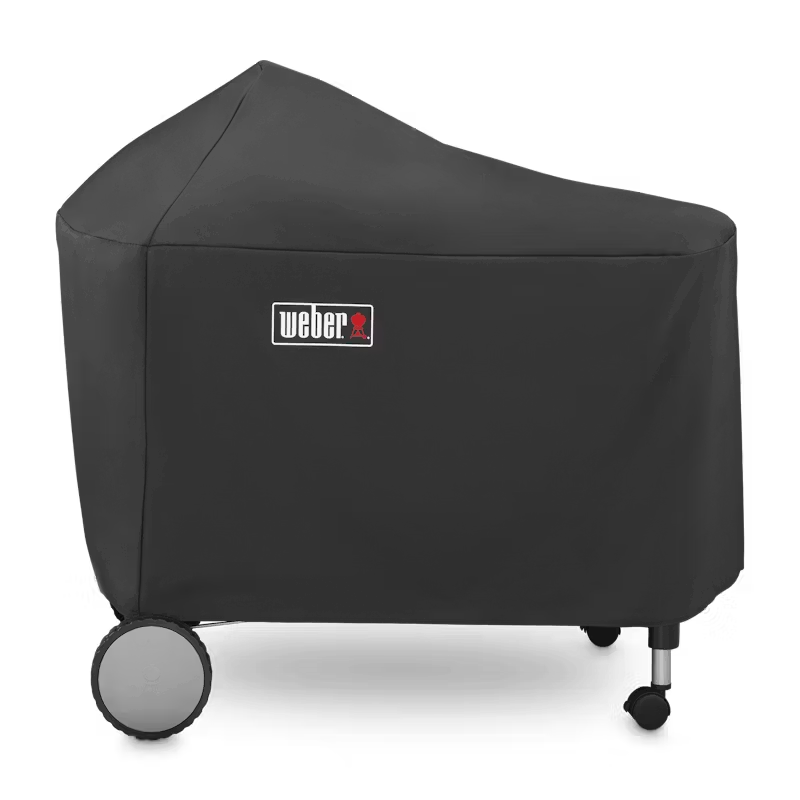 Weber Performer charcoal kettle grill draped with a black weatherproof cover on a backyard patio